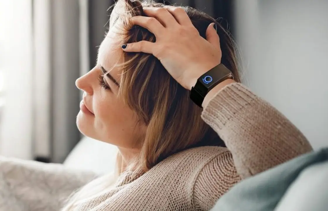 A white woman in her 30s wearing a Remedee wristband. She's smiling.